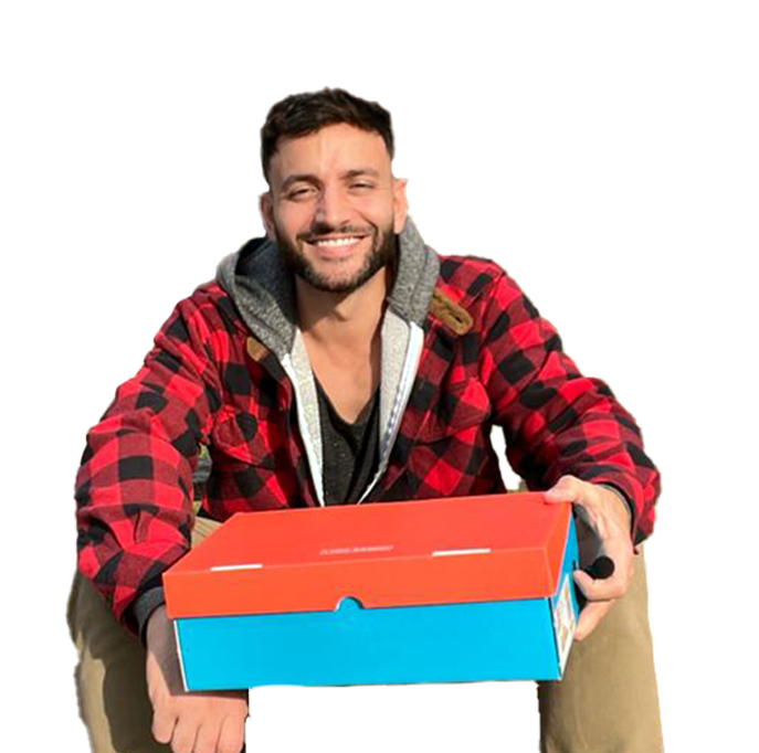 The founder of Luigi Sardo holding a shoe box and smiling
